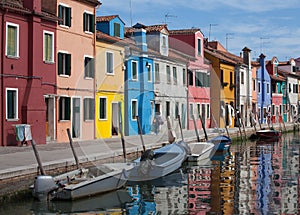 Houses of Burano and reflection in the water. Waterways with traditional boats and colorful facade