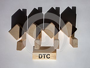 Houses created by shadows from wooden cubes. The word `DTC` on a wooden block. Direct to consumer concept. Beautiful white