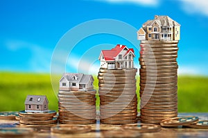 Houses of different size with on stacks of coins. Property, mortgage and real estate investment concept