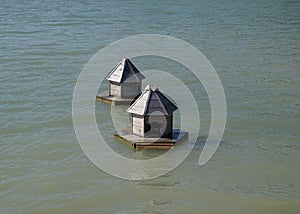 Houses for ducks on the lake. Taking care of ducks. Man-made nests for gray ducks