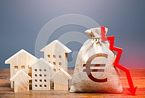 Houses and euro money bag with down arrow. Reducing maintaining cost, energy efficiency, saving. Realty crisis. Low rates on photo