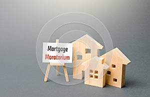 Houses figures and an easel sign with Mortgage Moratorium. Moratorium on loan repayments. Financial relief measures. Deferral