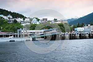 Houses On Hillside In The Alaskan Town Of Ketchikan. Snowcapped Mountains At The Background