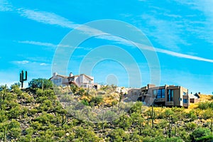 Houses on a hillside ridge in the sonora desert of Arizona with visble cactus and sprawling natural grasses and vegitation photo