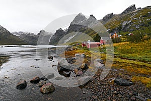 Panoramic view of a remote old fishing village at the coast in Vindstad with mountains in the background on Lofoten Islands Norway photo