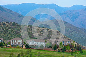 Houses on a mountainside with mountain peaks and green grass