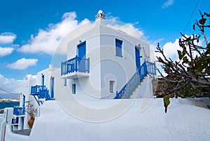 Houses in Mykonos, Greece. Whitewashed buildings with blue painted windows and doors on sunny sky. Typical architecture