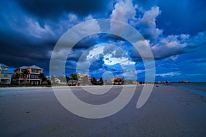 Houses near a beach against a dramatic cloudy sky in Estero Island, Florida