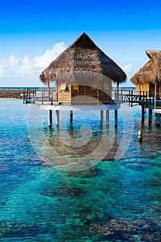 Houses over the transparent quiet sea water. Tahiti