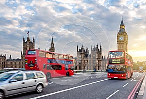 Houses of Parliament with Big Ben and double-decker buses on Westminster bridge at sunset, London, UK