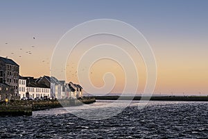 Houses by a river. calm pastel color sky in the background. Town urban scene. The Long walk, Galway city, Ireland. Dusk, sunset