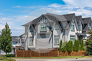 Houses with shingle roof against blue sky. Edge of roof shingles on top of the houses dark asphalt tiles on the roof