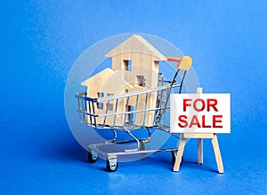 Houses in a shopping cart and an easel sign labeled for sale. Buying and selling real estate, hot offers and property valuation.