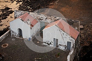 Houses or toilets outside of Lighthouse of Maria Pia with a cliff next to it, in the city of Praia, island of Santiago, Cape Verde