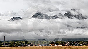 Houses in village and big mountains in clouds in background