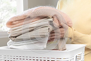 Housewife, asian young woman hand in many folding freshly shirts put the cloth in the basket after washing clean clothes and