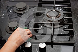 A housewife cleans the kitchen gas glass-ceramic black stove with a sponge. House cleaning