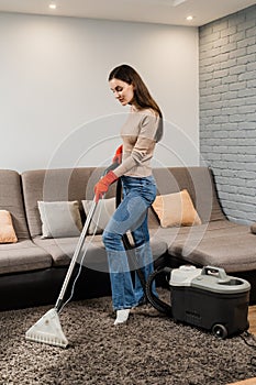 Housewife dry cleaning of carpet and removing dust, stains and dirt using mop extractor machine. Cleaner girl is