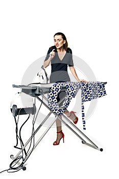 Housewife fatal woman in a black dress ironing things, blowing on a burnt finger. Isolated on a white background