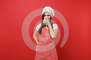 Housewife female chef cook or baker in striped apron, white t-shirt, toque chefs hat isolated on red wall background