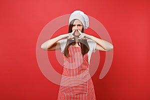 Housewife female chef cook or baker in striped apron, white t-shirt, toque chefs hat isolated on red wall background