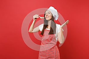 Housewife female chef cook or baker in striped apron, white t-shirt, toque chefs hat isolated on red wall background