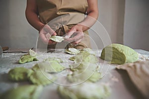 Na ruky z žena gazdinka šéfkuchár v béžový zástera tvorba knedle zelený cesto tavený špenát 