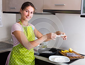 Housewife frying fish at kitchen