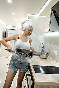 housewife with frying pan in the kitchen prerare breakfest after shower