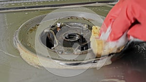 Housewife in gloves washes the dirty surface of a gas stove with a washcloth