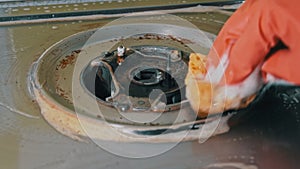 Housewife in gloves washes the dirty surface of a gas stove with a washcloth