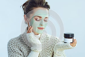 Housewife with green facial mask touching face