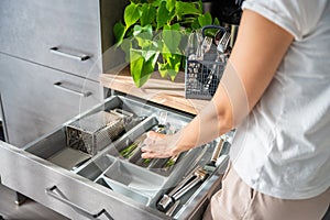 Housewife hands tidying up cutlery after dishwasher machine. Woman neatly assembling fork, spoon, knife accessories for