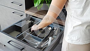 Housewife hands tidying up cutlery after dishwasher machine. Woman neatly assembling fork, spoon, knife accessories for