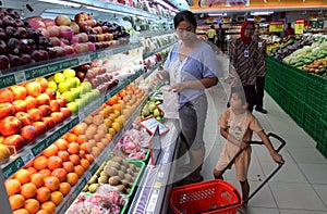 Housewife and her son shopping at one of the supermarkets in the city of Solo, Central Java Indonesia. they buy fruit and other ba