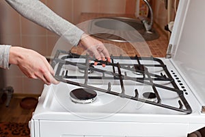 Housewife hold metal grates to clean the dirty kitchen gas stove. photo