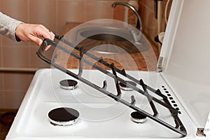 Housewife hold metal grates to clean the dirty kitchen gas stove. photo