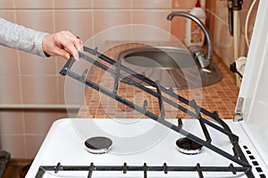 Housewife hold metal grates to clean the dirty kitchen gas stove. photo