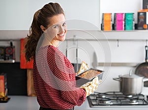 Housewife holding baking dish with bread