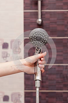 Housewife holds in her hand cleen and Ñlosed off rain shower head in the bathroom