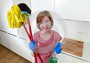 Housewife at home kitchen in gloves holding cleaning broom and mop and spray bottle