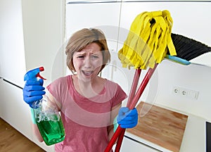 Housewife at home kitchen in gloves holding cleaning broom and mop and spray bottle