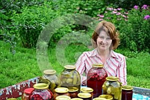 Housewife with homemade pickles and jams in garden