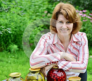 Housewife with homemade pickles and jams in garden