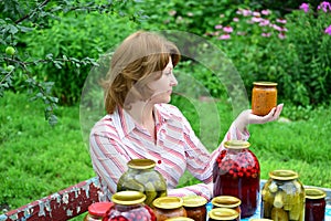 Housewife with homemade pickles and jams in garden