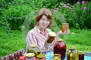 Housewife with homemade pickles and jams in garden