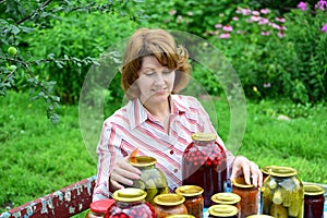 Housewife with homemade pickles and jams in garden