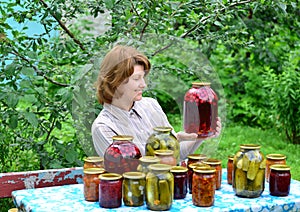 Housewife with homemade pickles and jams in garden