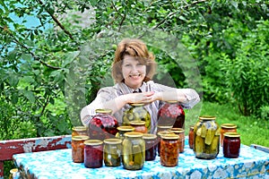 Housewife with homemade pickles and jams in garden