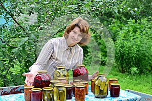 Housewife with homemade pickles and jams in garden